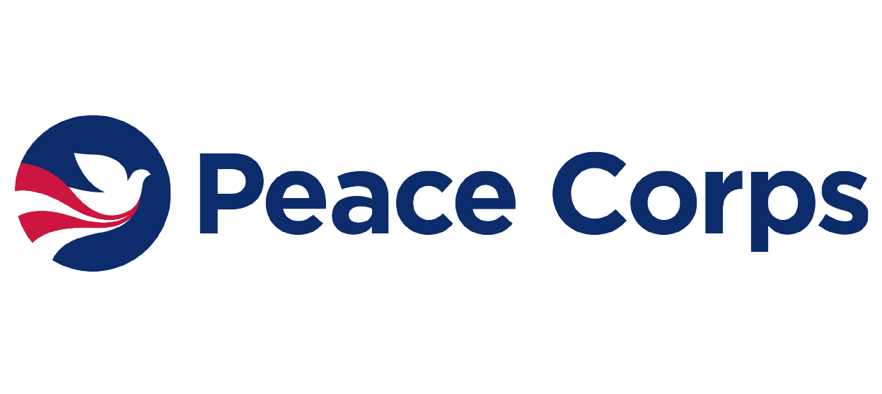 This is the logo for the United States Peace Corps. It is a blue circle with a white dove in the center. Underneath the dove, there are red and white stripes flowing under it. To the right of the circle are the words "Peace Corps."